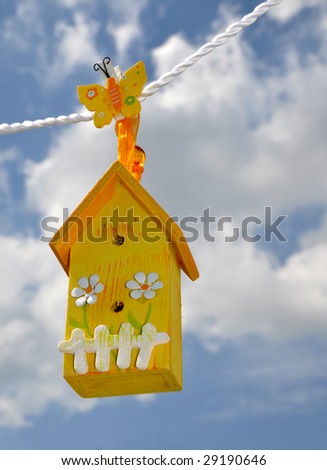 Toy house hanging on the rope against the beautiful sky