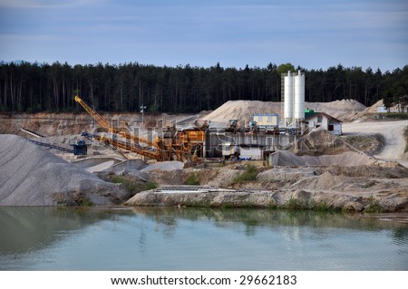 Stone quarry with silos, conveyor belts, and other mining equipment by the water
