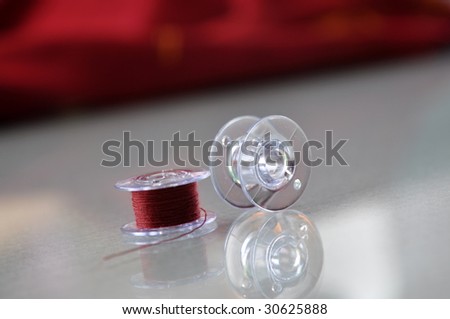 Bobbin with red thread and red fabric in the background