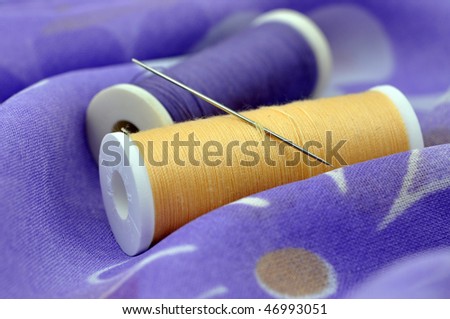 Needle and spools on floral cloth