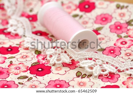 Spool and lace and on floral cloth