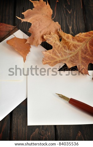 Fountain pen on empty letter with autumn leaves on a wooden table