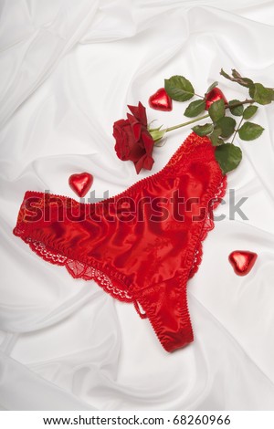 Red silk panties on white satin sheet.