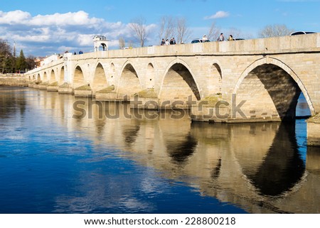 Edirne, Turkey - February 9, 2014: People passing by the Meric (River Evros) bridge. It\'s a historical and unique bridge which was built by architect Sinan in Edirne,Turkey.