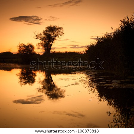 hunting and fishing in the pond. Evening landscape of the river and sky and trees reflected in water.