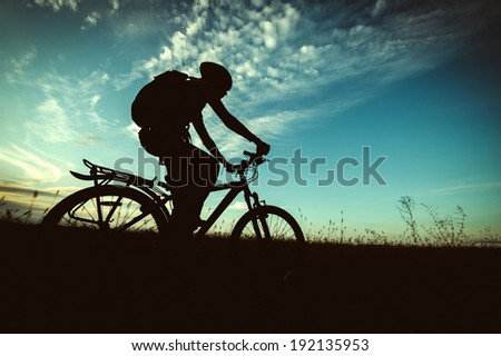 bike silhouette on the background of sky and fields at sunset