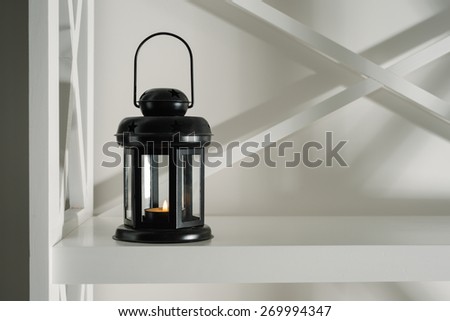interior and decor in the room. black lantern with a candle on a white bookcase in the design of the room.