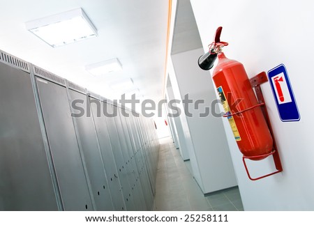 a red fire-extinguisher hangs on a white wall in an apartment