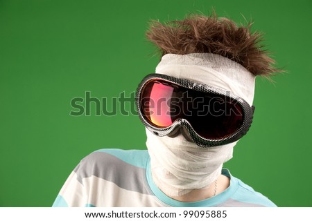 Extreme winter sport, a snowboarder with a bandaged head in a mask on a green background.