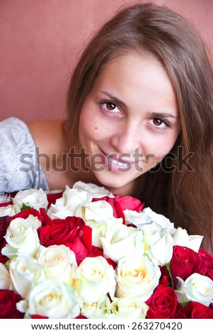 Smiling girl holding a large bouquet of red and white roses.