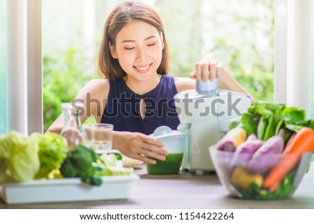 close up of young woman with blender and green vegetables making detox shake or smoothie at home. Green Healthy Food Concept.