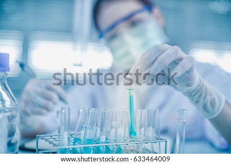 Asian women scientist with test tube making research in clinical laboratory.Science, chemistry, technology, biology and people concept