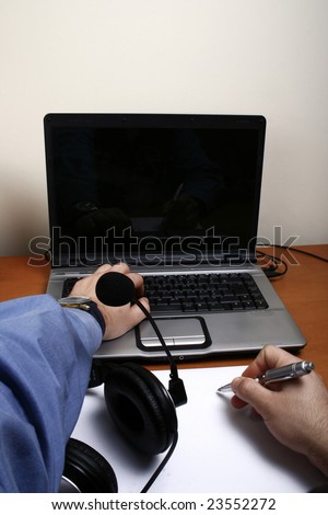 Business man working with the computer and writing with headphones on the table