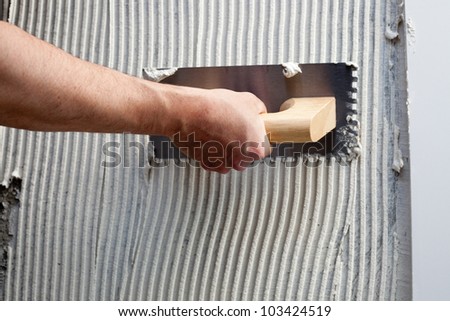 construction notched trowel with white cement mortar for tiles work