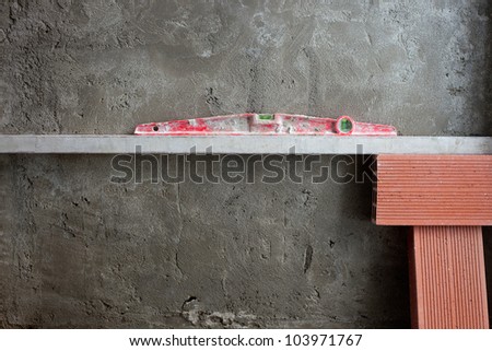 bubble spirit level tool in red on costruction cement wall with bricks