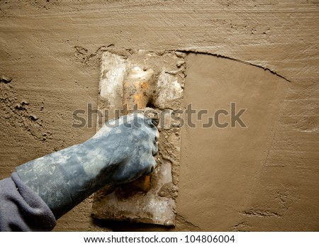 dirty trowel with glove hand plastering cement mortar in the wall