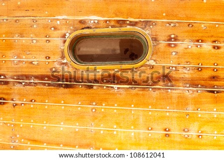 boat oval aged brass porthole in wooden hull with caulking putty and screw