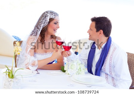 Couple in wedding day cheering with red wine in banquet table