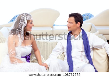 Couple in wedding day relaxed in white terrace couch outdoor