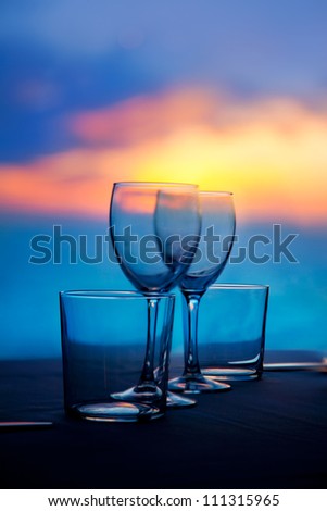 Dish of cups and crystal transparent glasses on a sea sunset table
