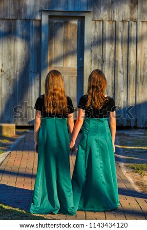 Long dress twin teen sisters hand in hand at the park sooden cabin