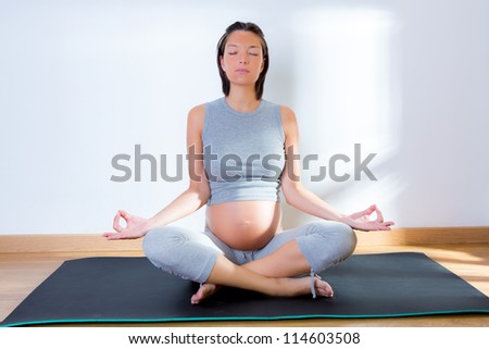 Beautiful pregnant woman at gym fitness exercise practicing yoga on mat