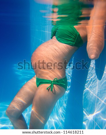 Beautiful pregnant woman underwater blue pool relaxed