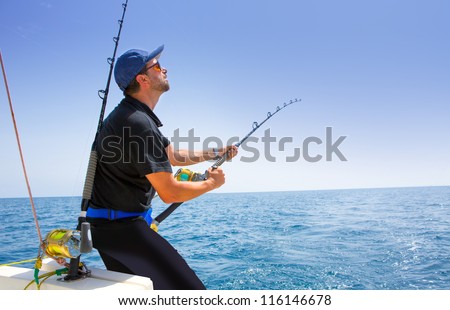 Blue Sea Offshore Fishing Boat With Fisherman Holding Rod In Action