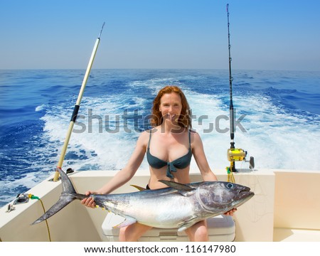 beautiful bikini fisher woman holding big bluefin tuna catch on boat deck