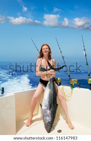 beautiful bikini fisher woman holding big bluefin tuna catch on boat deck