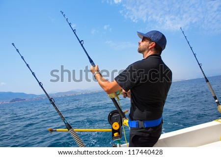 blue sea fisherman in trolling boat in action with downrigger and rod