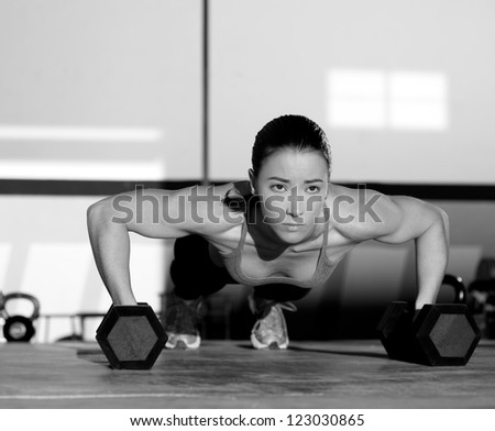 Gym woman push-up strength pushup exercise with dumbbell in a fitness workout