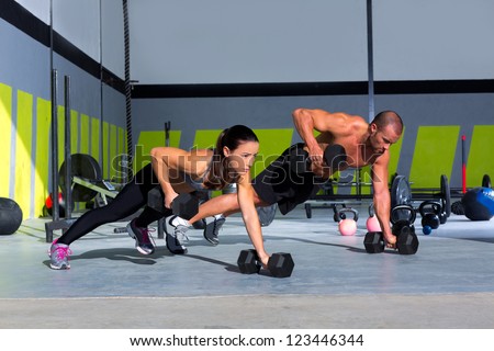 Gym man and woman push-up strength pushup with dumbbell in a fitness workout
