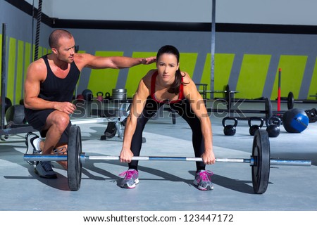 gym personal trainer man with weight lifting bar woman workout in fitness exercise
