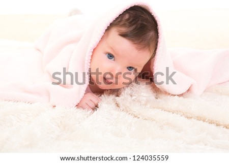 baby girl under hidden pink blanket on winter white fur background