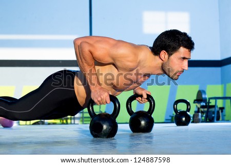 Gym man push-up strength pushup exercise with Kettlebell in a workout