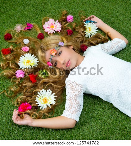 Blond spring children girl with flowers on hair over green grass floor