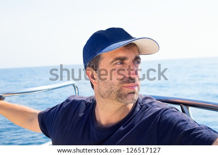 Sailor man at boat bow with cap looking away the sea while sailing
