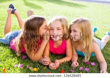 children friend girls group playing whispering on flowers grass in vacations