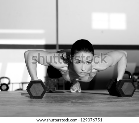 Gym woman push-up strength pushup exercise with dumbbell in a workout - stock photo