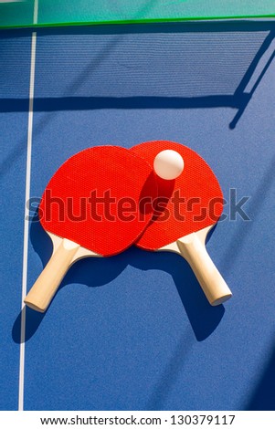 table tennis ping pong two paddles and white ball on blue board