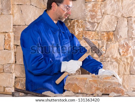 Masonry mason stonecutter man with hammer working on stone wall construction