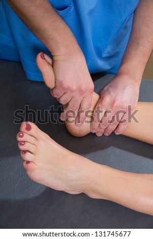 Ankle joint mobilization therapy of doctor man to patient woman in hospital
