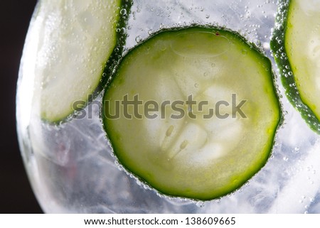 Gin tonic cocktail with cucumber and ice  macro closeup on black