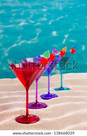 colorful cocktail in a row with cherry on tropical sand beach of turquoise sea
