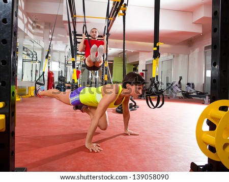 Crossfit fitness TRX training exercises at gym woman push-up and dip rings man workout