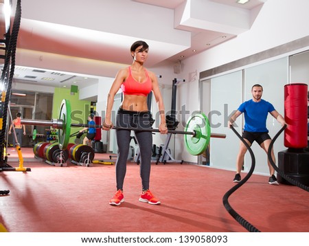 Crossfit fitness gym weight lifting bar woman and man battling ropes workout