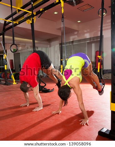 Crossfit fitness TRX training exercises at gym woman and man push-up pushup