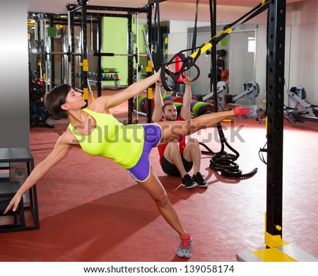Crossfit fitness TRX training exercises at gym woman and dip rings man workout