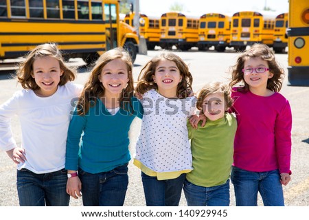 school girls friends sisters in a row walking from yellow school bus lot